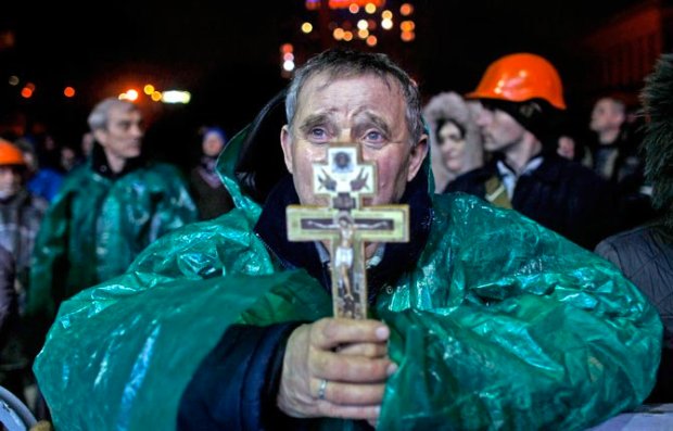Ukraine Christian holds a crucifix as he prays in Kiev, Ukraine, Thursday, Feb. 20, 2014  The deposed President vowed to defeat "terrorists" responsible for seizing weapons and burning down buildings. AP Photo/ Marko Drobnjakovic