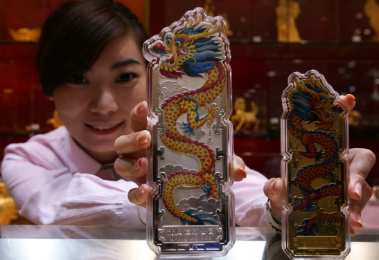 An employee shows off silver and gold bullion bars engraved with dragons at a gold shop in Beijing.