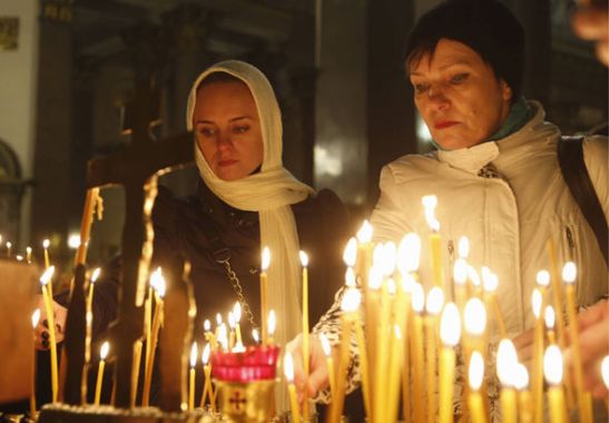 People light candles inside an Orthodox church in St Petersburg