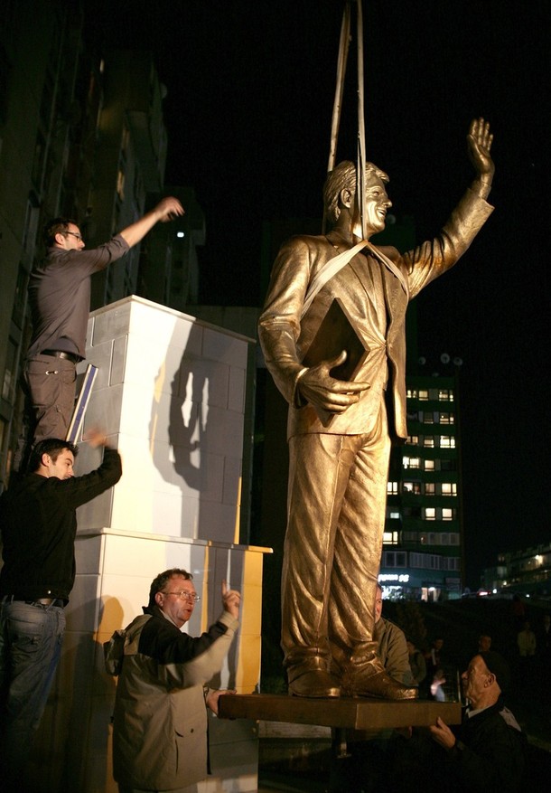 Workers install a monument to former U.S. President Bill Clinton on Bill Clinton Boulevard in Pristina